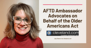 AFTD Ambassador Advocates on Behalf of the Older Americans Act Judy Bearer smiles into the camera. She has dark blonde hair and is wearing a deep red turtleneck and multi-colored glasses.